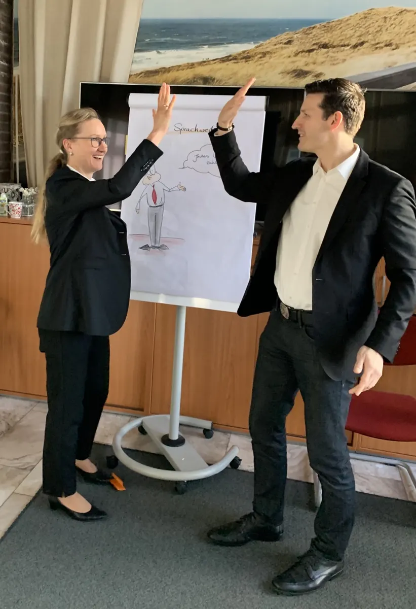 Jörg Vogelgesang klatscht mit einer Teilnehmerin am Flipchart ab
